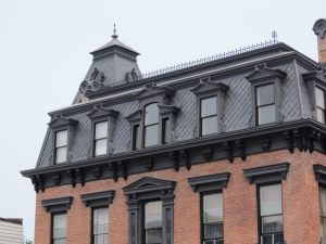 The mansard roof is the character-defining feature of the Second Empire style. A mansard is essentially a hipped gambrel. The lower roof, between the eaves and upper cornice, is most often covered in slate.