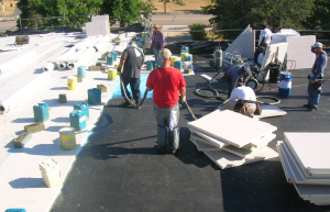 PHOTO 6: On this school, the existing EPDM roof membrane is being utilized as a vapor retarder. After cleaning, two layers of insulation are being installed in full- coverage spray foam. The amount of new insulation above the existing membrane was determined by dew-point calculations.