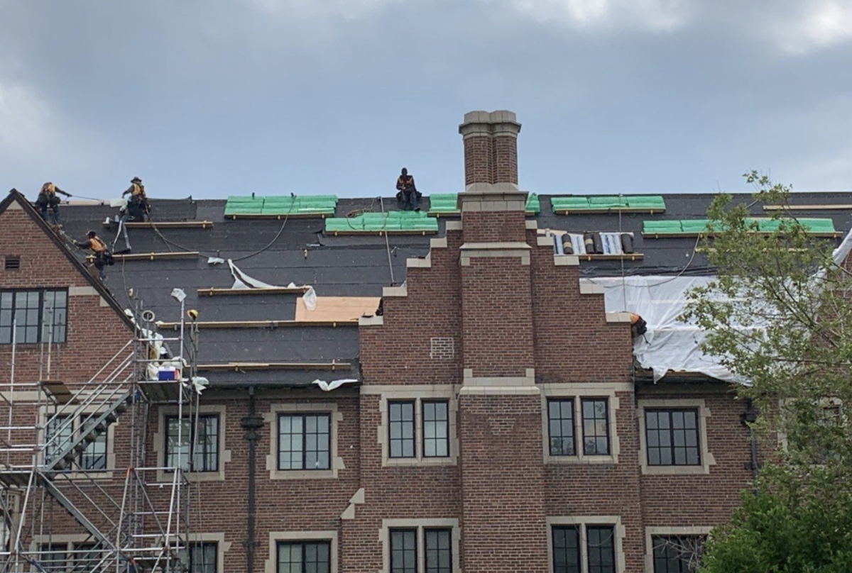 The image shows workers working high up at a steep angle which poses reroofing challenges